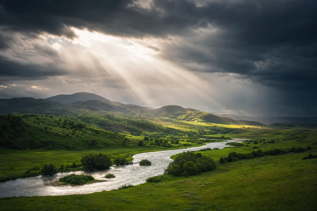 Vallée verdoyante sous un ciel orageux, trouée de lumière entre les nuages